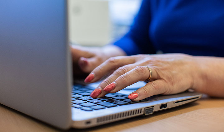  Kuvituskuva: nainen kirjoittaa kannettavan tietokoneen näppäimistöllä.